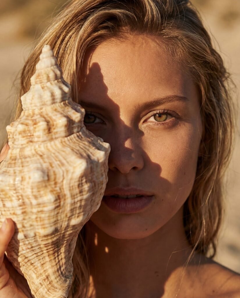 woman, seashell, beach, summer, portrait, green eyes, blonde, golden hour, sunset, nature, beauty, ocean, coast, vacation, skincare, natural, conch, sea, sand, travel, lifestyle, sunlight, close-up, tropical, marine, outdoor