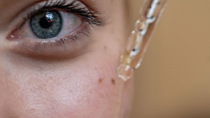 Close-up image of a person applying skincare serum using a dropper.