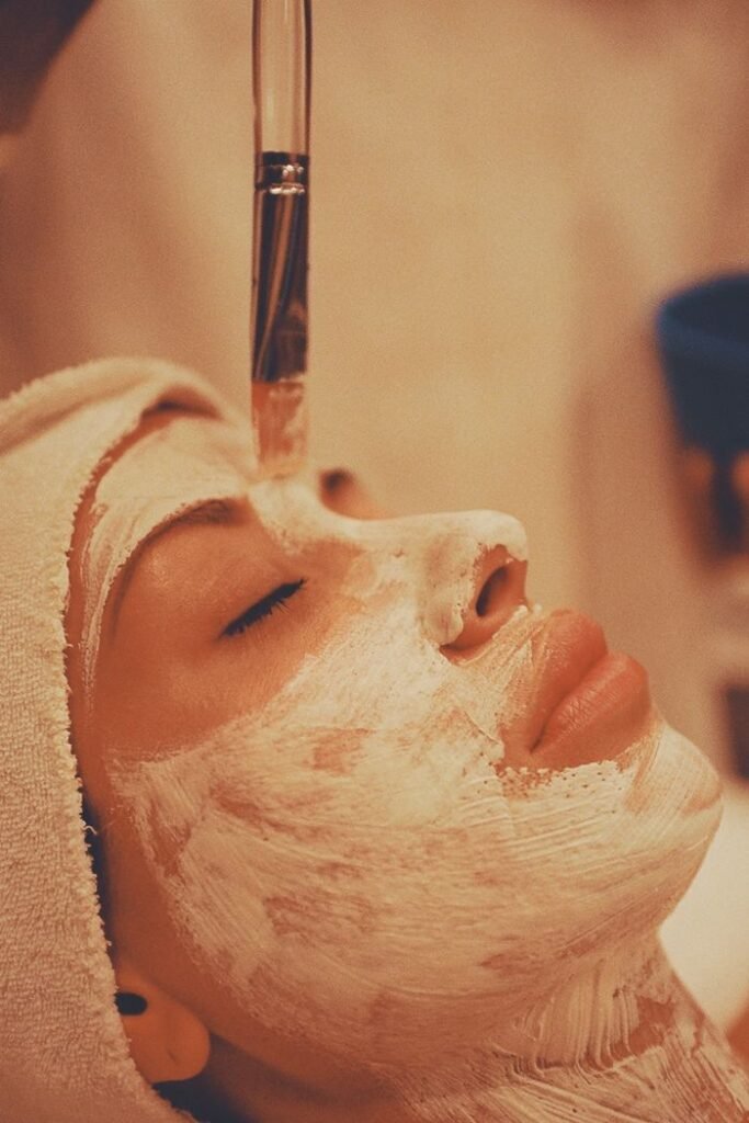 Adult woman receiving a soothing facial mask application at a modern spa.
