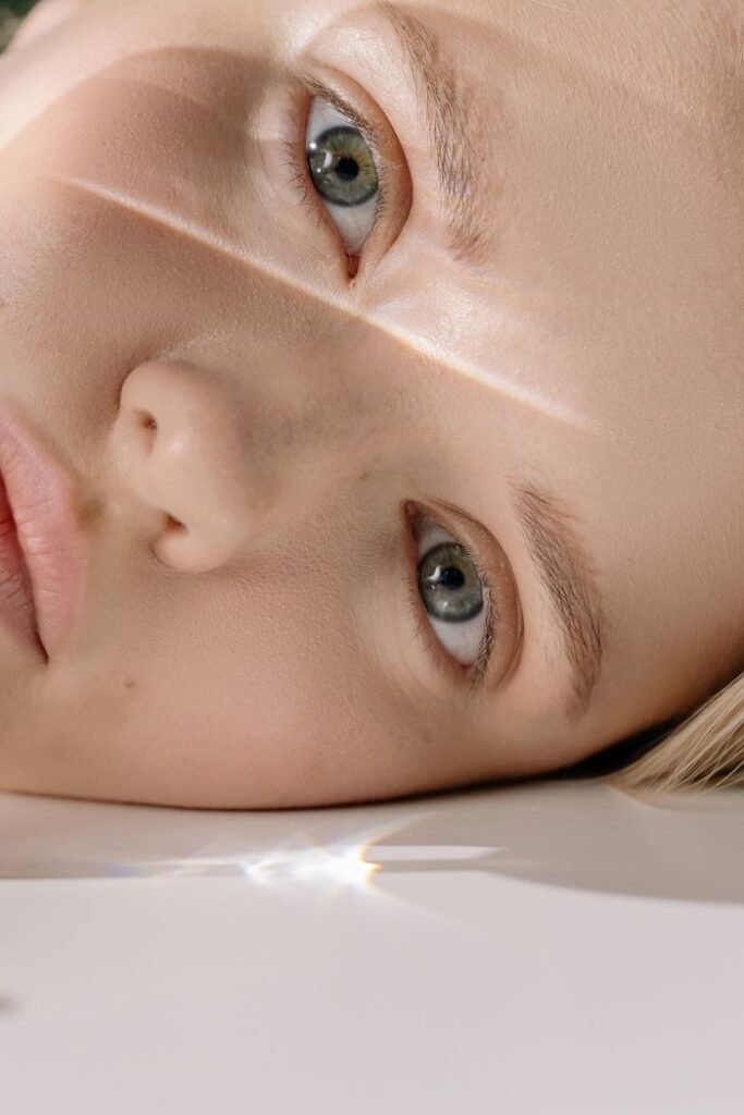 Detailed close-up of a woman's face with striking green eyes reflecting light.