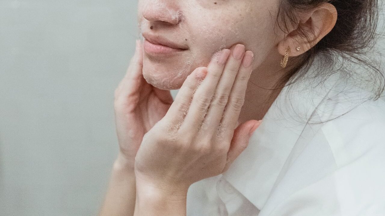 Woman applying face wash, embracing skincare and self-care indoors.