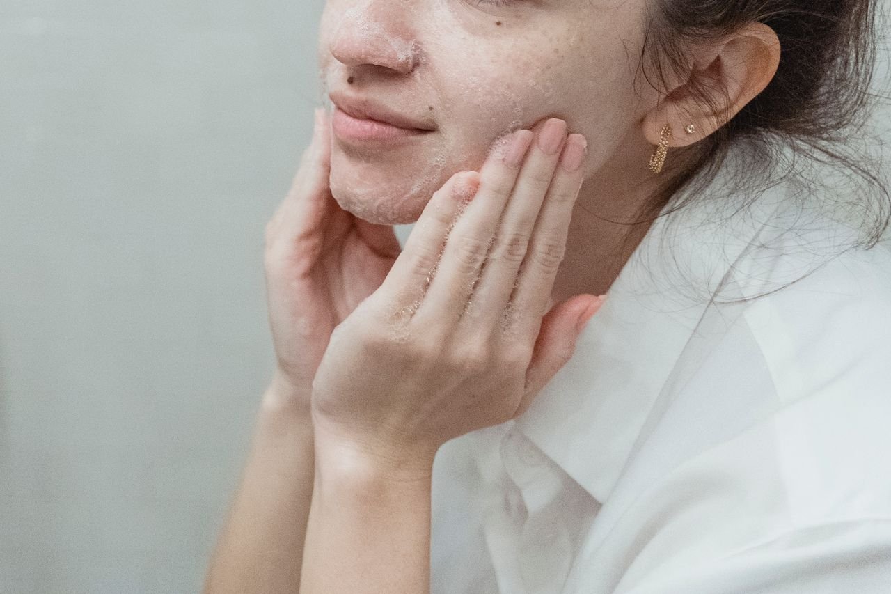 Woman applying face wash, embracing skincare and self-care indoors.